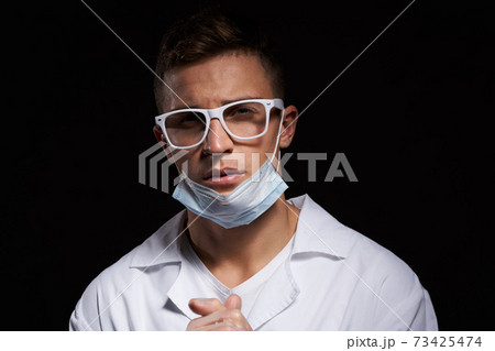 doctor in protective medical mask and glasses on black background close-up portrait cropped view 73425474