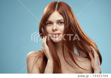 Pretty woman holding hair in hands grooming naked shoulders cropped view blue background Pretty woman holding hair in hands grooming naked shoulders cropped view blue background 73425704