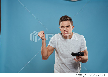 A man with a joystick in his hands entertainment leisure technology video games blue background white t-shirt A man with a joystick in his hands entertainment leisure technology video games blue background white t-shirt 73427951