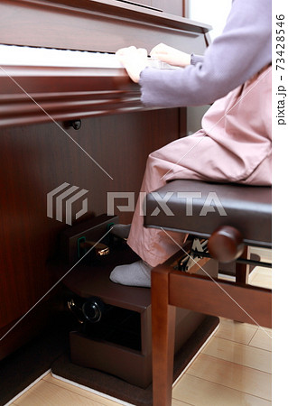 補助ペダルを使ってアップライトピアノを弾く5歳の女の子 73428546