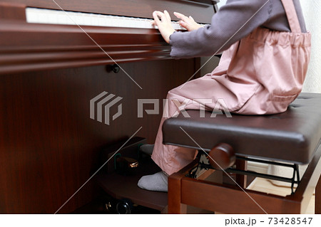 補助ペダルを使ってアップライトピアノを弾く5歳の女の子 73428547