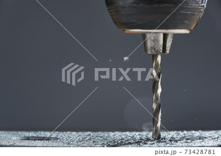 Metal drilling closeup in metal workshop on gray background. Hole being drilled into metal. 73428781