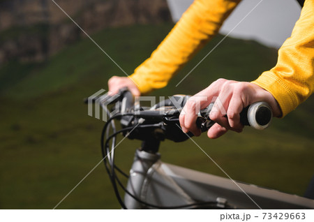 Close-up of female hands holding the handlebars of a mountain bike in the summer in the mountains 73429663