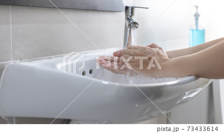 Man is washing his hands in a sink sanitizing the colona virus for sanitation and reducing the spread of COVID-19 spreading throughout the world, Hygiene ,Sanitation concept. 73433614
