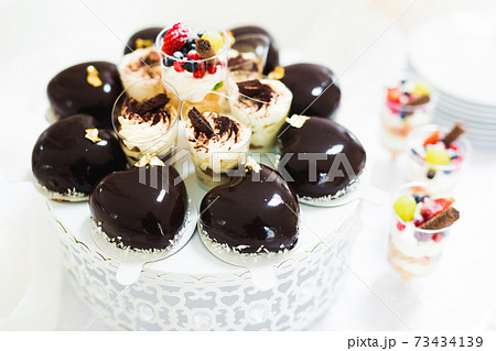Delicious and tasty dessert table with cupcakes and shots at reception closeup Delicious and tasty dessert table with cupcakes and shots at reception closeup 73434139