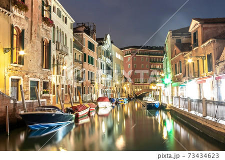 Evening view of illuminated old architecture, floating boats and light reflections in canals water in Venice, Italy. Evening view of illuminated old architecture, floating boats and light reflections in canals water in Venice, Italy. 73434623