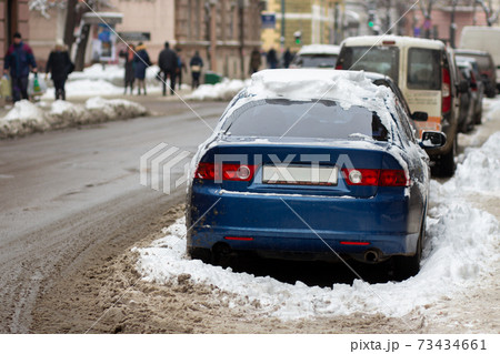 Cars parked on a side of city street covered with dirty snow in winter. Cars parked on a side of city street covered with dirty snow in winter. 73434661