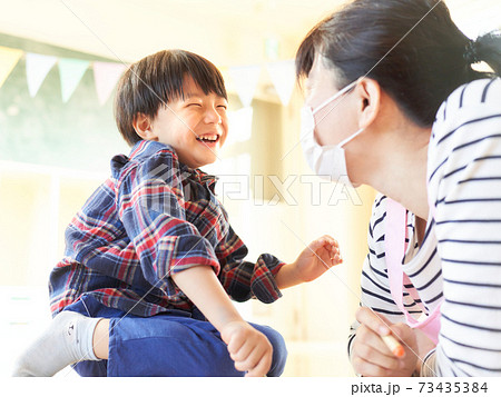 笑顔の男の子とマスク姿の保育士 73435384