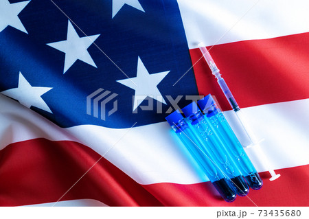 Injection usa. Medical syringe with needle for protection flu virus and coronavirus. Covid vaccine on american flag background. Concept fight against virus covid-19. 73435680