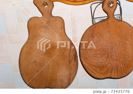 Wooden cutting boards in the shape of an apple and a pear hang on the wall 73435770