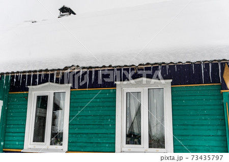 Ice icicles and Village house covered with snow, snowy winter, remote village, Russian village 73435797