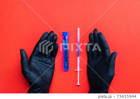Injection. Doctor hand in medical glove hold syringe with needle for protection flu virus and coronavirus. Covid vaccine isolated on red. Nurse or doctor. Liquid drug or narcotic. Injection. Doctor hand in medical glove hold syringe with needle for protection flu virus and coronavirus. Covid vaccine isolated on red. Nurse or doctor. Liquid drug or narcotic. 73435944