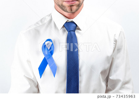 November. Hipster men in bright shirt, cyan tie with blue ribbon in hands on white background. Awareness prostate cancer of men health. Supporting people living and illness. November. Hipster men in bright shirt, cyan tie with blue ribbon in hands on white background. Awareness prostate cancer of men health. Supporting people living and illness. 73435963