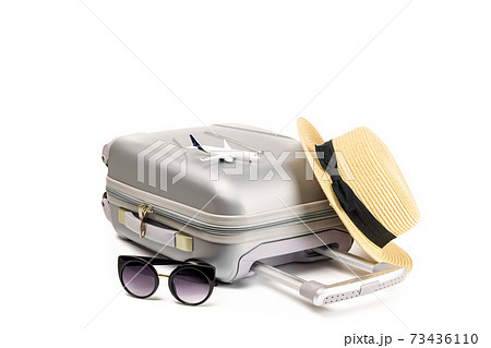 Baggage isolated. Travel accessories with suitcase, straw hat, toy airplane in minimal trip vacation concept isolated on white background. Summer vacation and product advertisement concept. 73436110