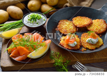 Crunchy potato pancakes with smoked salmon and chives quark served in an iron frying pan 73436650