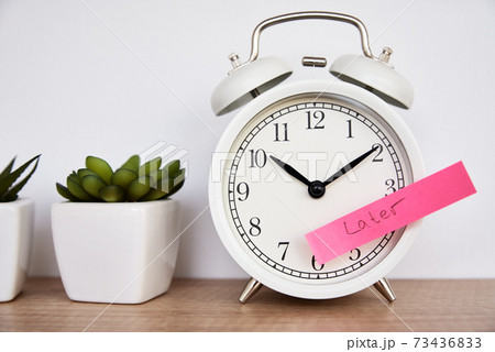 Procrastination and delay concept. Sticky note with word later on white alarm clock. Urgency time Procrastination and delay concept. Sticky note with word later on white alarm clock. Urgency time 73436833