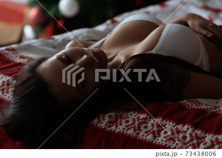 Alluring young lady relaxing on bed with closed eyes during Christmas holidays Alluring young lady relaxing on bed with closed eyes during Christmas holidays 73438006