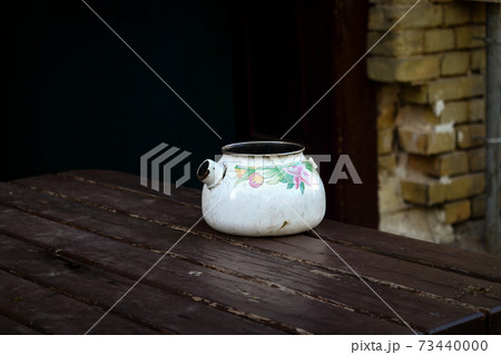 Old broken kettle standing on wooden table 73440000