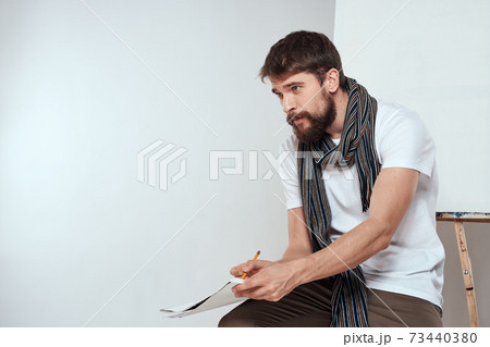 Male artist sitting on chair drawing brush easel hobby Creative light background Male artist sitting on chair drawing brush easel hobby Creative light background 73440380