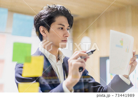 会議室で透明ボードを使って打合せするビジネスマン 73441989
