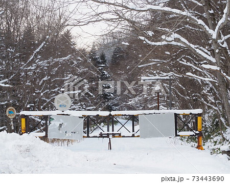 雪に覆われた古びた通行止め 73443690