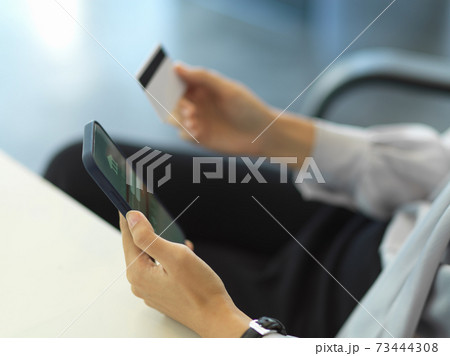 Businesswoman hand holding credit card while online paying on smartphone 73444308