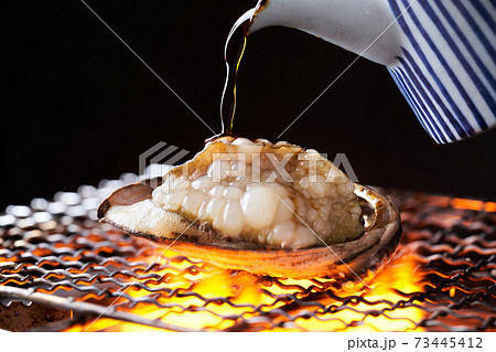 活アワビの踊り焼きに醤油をかけるの写真素材