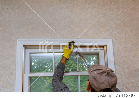 The process of removing an old wooden window from an opening in a house before replacing it with a new one. 73445797
