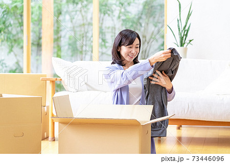 リビングで段ボールに荷造りするミドル女性 リビングで段ボールに荷造りするミドル女性 73446096