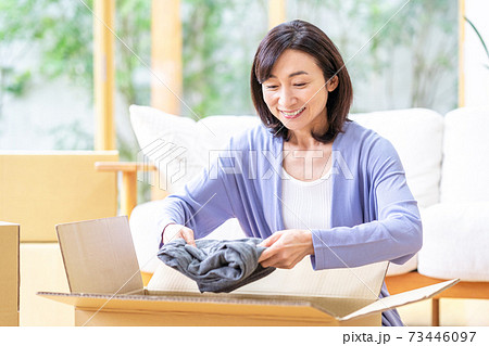 リビングで段ボールに荷造りするミドル女性 73446097