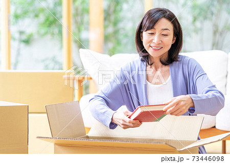 リビングで段ボールに荷造りするミドル女性 リビングで段ボールに荷造りするミドル女性 73446098
