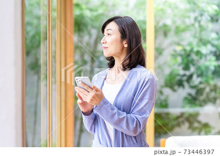 リビングでスマホを操作するミドル女性 リビングでスマホを操作するミドル女性 73446397
