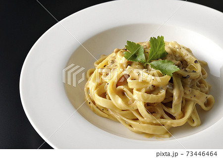 三つ葉が乗っているトリュフクリームの平打ちパスタを黒背景で撮影 73446464