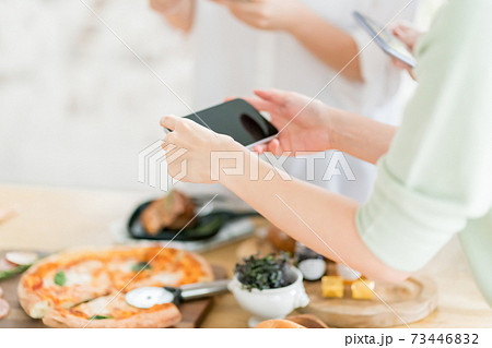 スマホで料理写真を撮る女性の写真素材