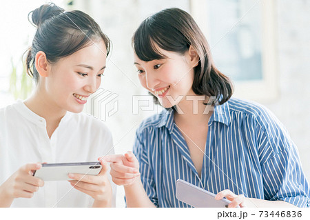 スマホを見せ合う姉妹 73446836