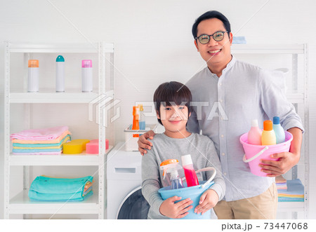 Father and Son holding bucket full of cleaning liquid bottles ready to do housework together. 73447068