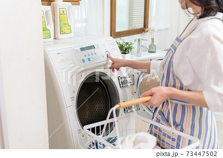 洗濯機に洗濯物を入れるミドル女性の写真素材