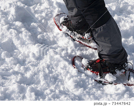 雪山でアイゼン・ワカン （かんじき）を装着して歩く男性登山者の写真