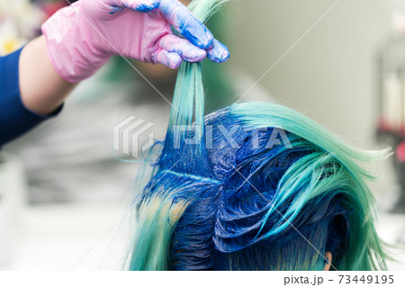 Hairdressers raise shock of blue hair of client during coloring process 73449195