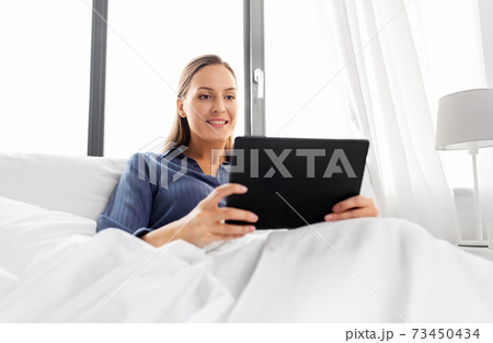 young woman with tablet pc in bed at home bedroom 73450434