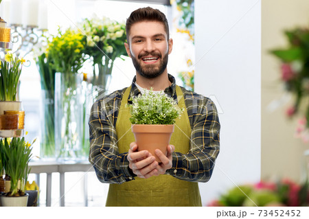 happy male seller with plant at flower shop 73452452
