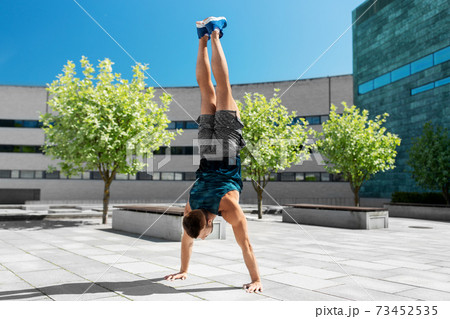 young man exercising and doing handstand outdoors young man exercising and doing handstand outdoors 73452535