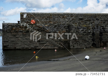Harbour wall with stairs and buoys on sand at low tide. 73452731