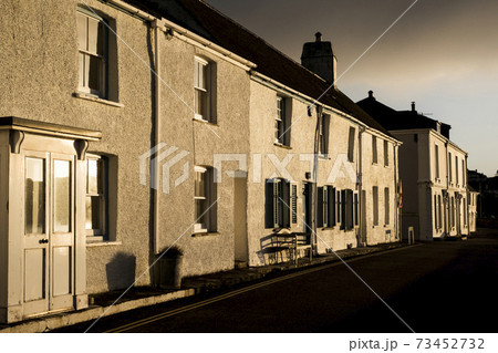 View along narrow terraced houses along a street at sunrise. 73452732