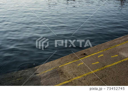 High angle close up of yellow footprints and lines painted on asphalt ground in a harbour. 73452745