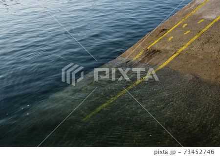 High angle close up of yellow footprints and lines painted on asphalt ground in a harbour. 73452746