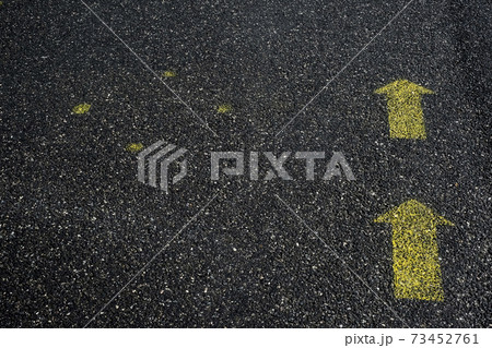 High angle close up of yellow arrow symbols painted on asphalt ground. 73452761