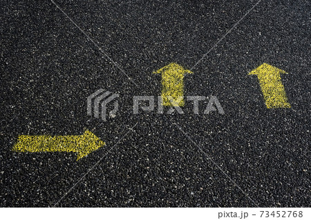 High angle close up of yellow arrow symbols painted on asphalt ground. 73452768