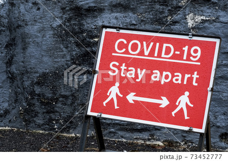 Close up of red and white Covid-19 distancing sign. 73452777