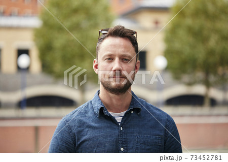 Man with a beard standing outdoors in a city on a quiet street 73452781